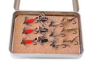 Full tackle box of fly fishing flies in Washington river - SuperStock